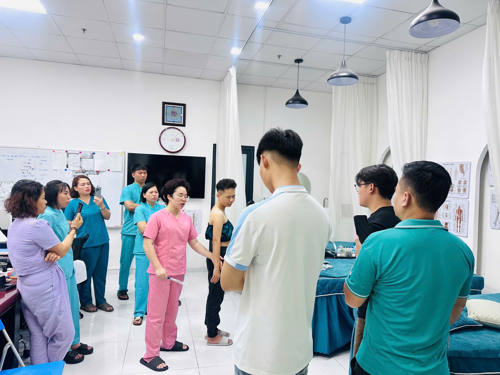 Chuyên gia Thiên An mặc đồng phục hồng hướng dẫn học viên trong lớp thực hành